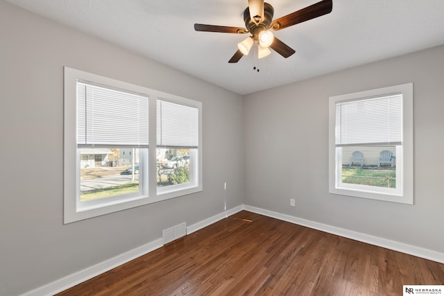 unfurnished room featuring a wealth of natural light, ceiling fan, and dark hardwood / wood-style floors