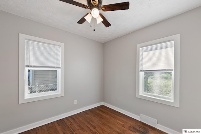 empty room with a textured ceiling, ceiling fan, and dark hardwood / wood-style floors