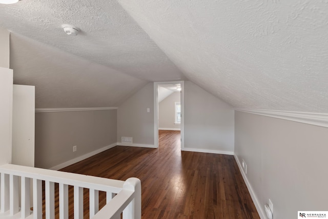 bonus room featuring lofted ceiling, dark hardwood / wood-style flooring, and a textured ceiling