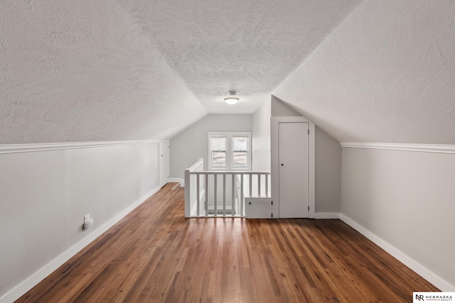 bonus room featuring a textured ceiling, vaulted ceiling, and dark hardwood / wood-style floors