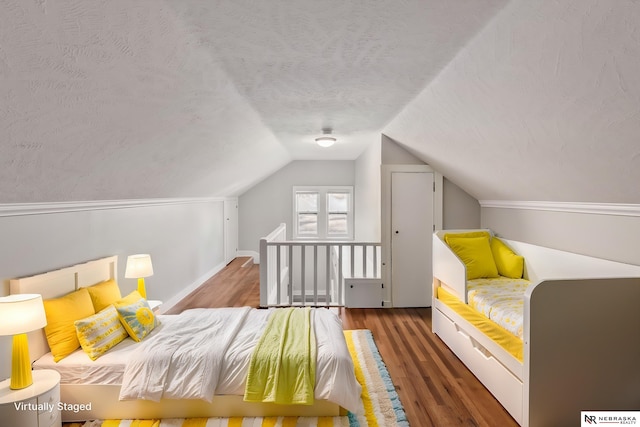 bedroom featuring a textured ceiling, dark hardwood / wood-style floors, and lofted ceiling