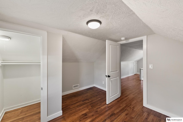 bonus room with a textured ceiling, dark wood-type flooring, and lofted ceiling