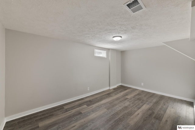 basement with a textured ceiling and dark hardwood / wood-style floors