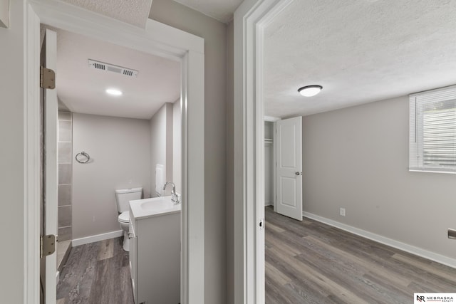 bathroom featuring hardwood / wood-style floors, vanity, a textured ceiling, and toilet