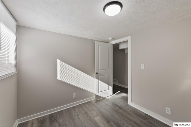 spare room with dark hardwood / wood-style floors and a textured ceiling