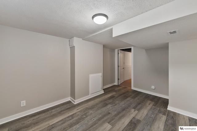 basement with a textured ceiling and dark hardwood / wood-style flooring