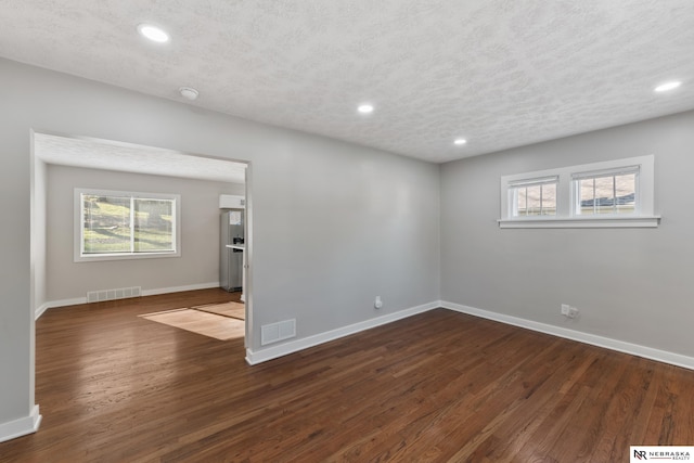 spare room with a textured ceiling and dark hardwood / wood-style floors