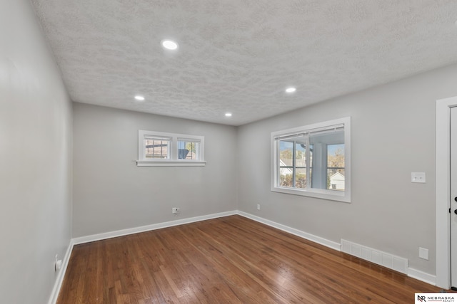 unfurnished room featuring hardwood / wood-style floors and a textured ceiling