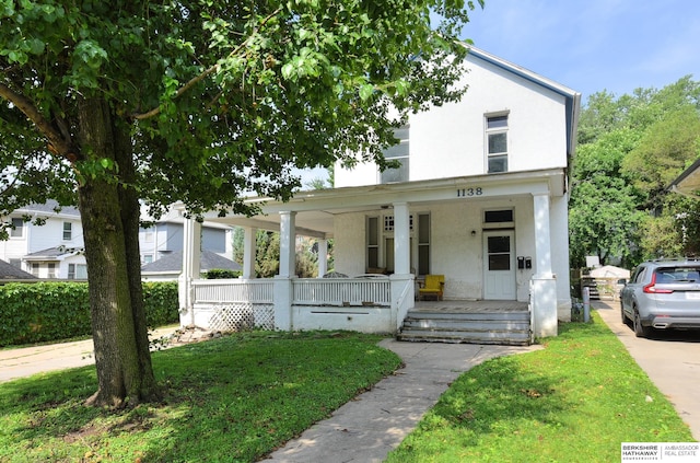 view of front of home with covered porch and a front lawn