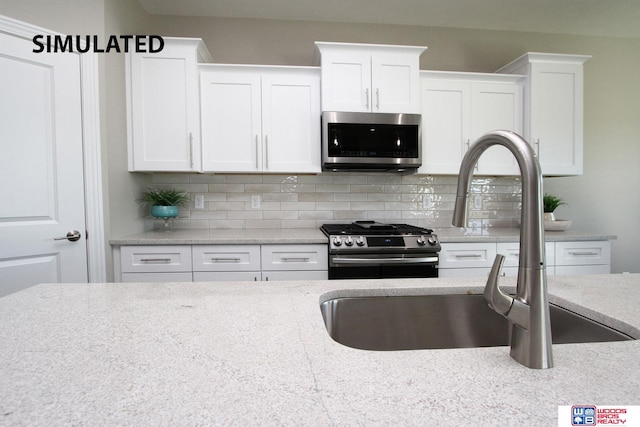 kitchen with backsplash, sink, white cabinets, and appliances with stainless steel finishes