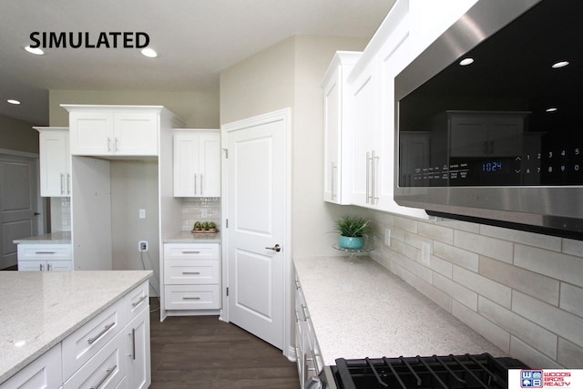 kitchen with white cabinets, decorative backsplash, light stone countertops, and dark wood-type flooring