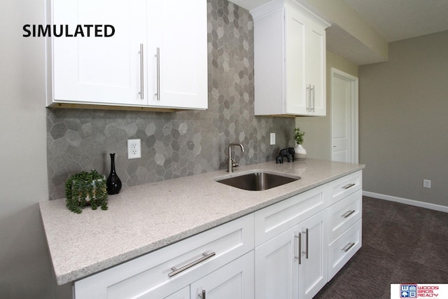 kitchen featuring dark carpet, sink, decorative backsplash, light stone counters, and white cabinetry