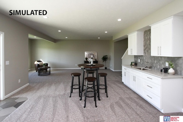 kitchen featuring decorative backsplash, a kitchen bar, light colored carpet, sink, and white cabinetry