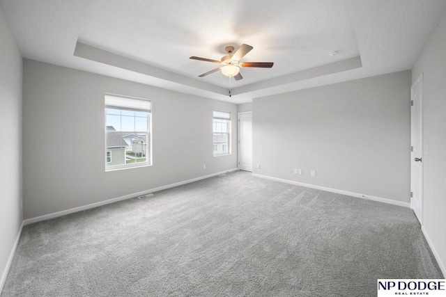 spare room featuring carpet flooring, ceiling fan, and a tray ceiling