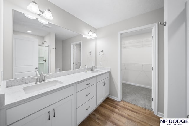 bathroom with toilet, vanity, a shower with door, and hardwood / wood-style flooring