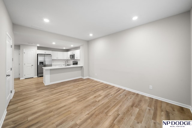 kitchen featuring sink, stainless steel appliances, light hardwood / wood-style flooring, kitchen peninsula, and white cabinets