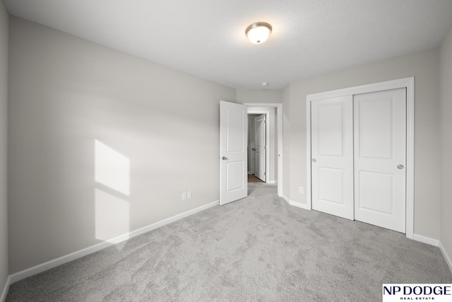 unfurnished bedroom with light colored carpet and a closet