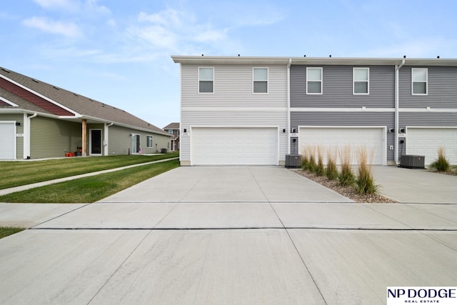 view of front of property with central AC, a front lawn, and a garage