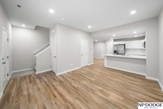 unfurnished living room featuring sink and light hardwood / wood-style flooring