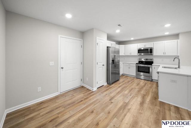 kitchen featuring white cabinets, sink, appliances with stainless steel finishes, and light hardwood / wood-style flooring