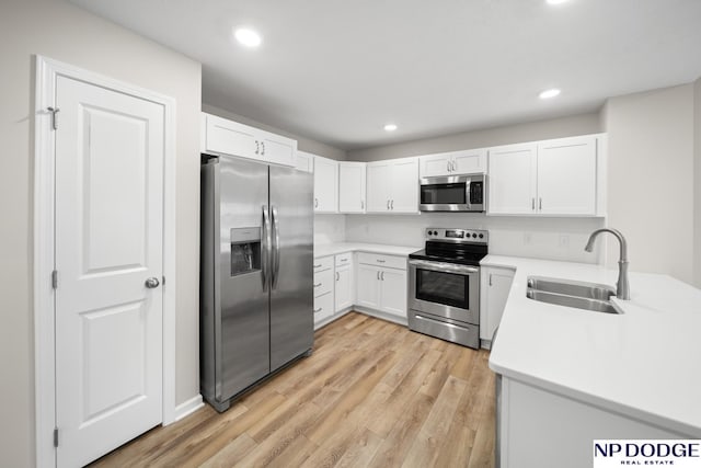 kitchen with sink, white cabinets, light wood-type flooring, and appliances with stainless steel finishes