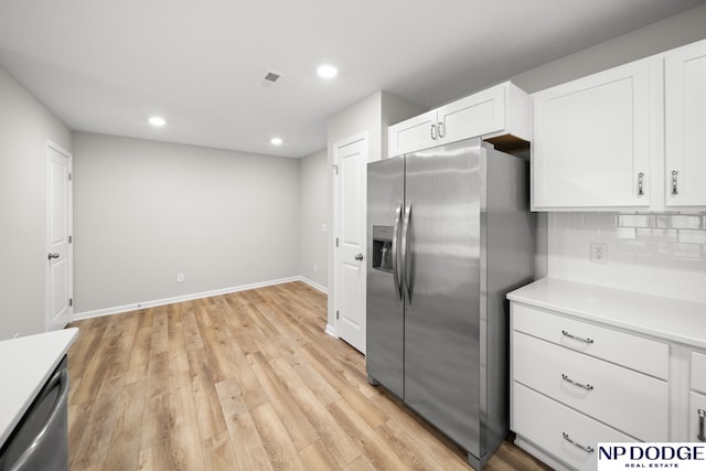 kitchen featuring decorative backsplash, white cabinetry, stainless steel appliances, and light hardwood / wood-style floors