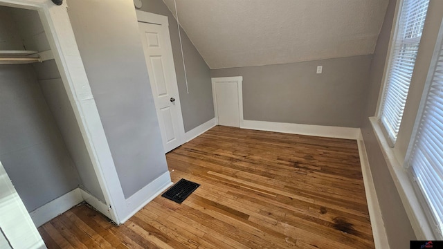 interior space with hardwood / wood-style floors, lofted ceiling, and a textured ceiling