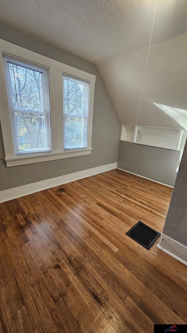 bonus room featuring wood-type flooring, plenty of natural light, and lofted ceiling