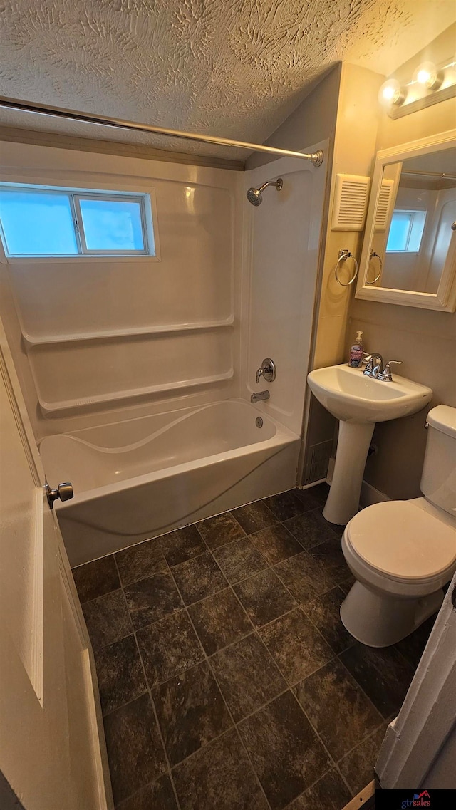 bathroom featuring toilet, a textured ceiling, and shower / washtub combination