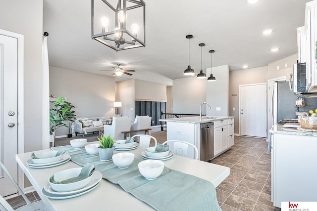 dining space with ceiling fan with notable chandelier and sink