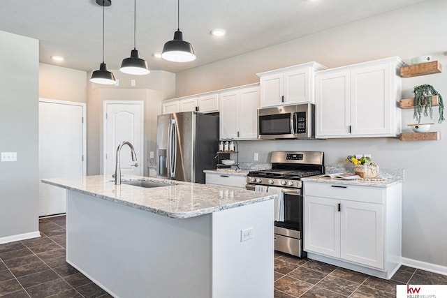 kitchen with white cabinetry, sink, hanging light fixtures, stainless steel appliances, and an island with sink