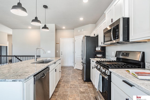 kitchen with appliances with stainless steel finishes, a kitchen island with sink, sink, decorative light fixtures, and white cabinetry