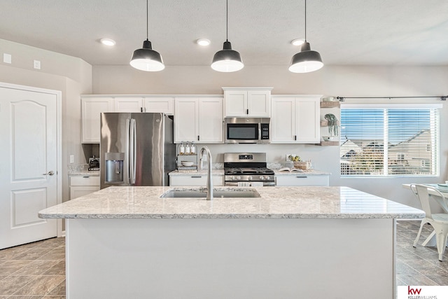 kitchen featuring light stone countertops, white cabinetry, stainless steel appliances, and hanging light fixtures