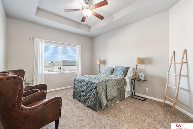 bedroom with ceiling fan, light colored carpet, and a tray ceiling