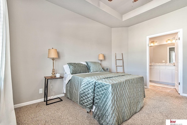 carpeted bedroom with a tray ceiling, ensuite bathroom, and ceiling fan