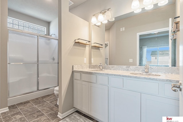 bathroom with toilet, an enclosed shower, and vanity