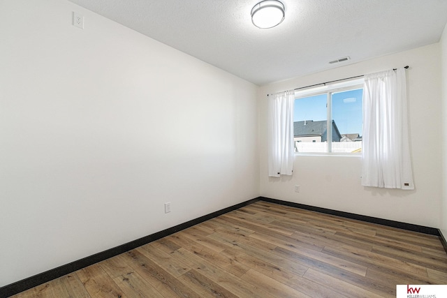 spare room with a textured ceiling and hardwood / wood-style flooring