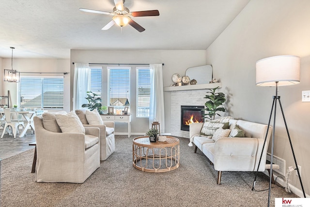 carpeted living room featuring a textured ceiling, ceiling fan, a fireplace, and vaulted ceiling