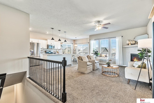 living room featuring a textured ceiling, light colored carpet, ceiling fan, and a tiled fireplace