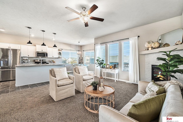 carpeted living room featuring ceiling fan, sink, and a textured ceiling