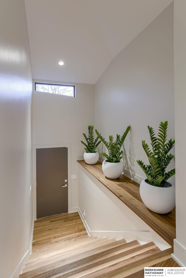 stairway featuring vaulted ceiling and hardwood / wood-style flooring