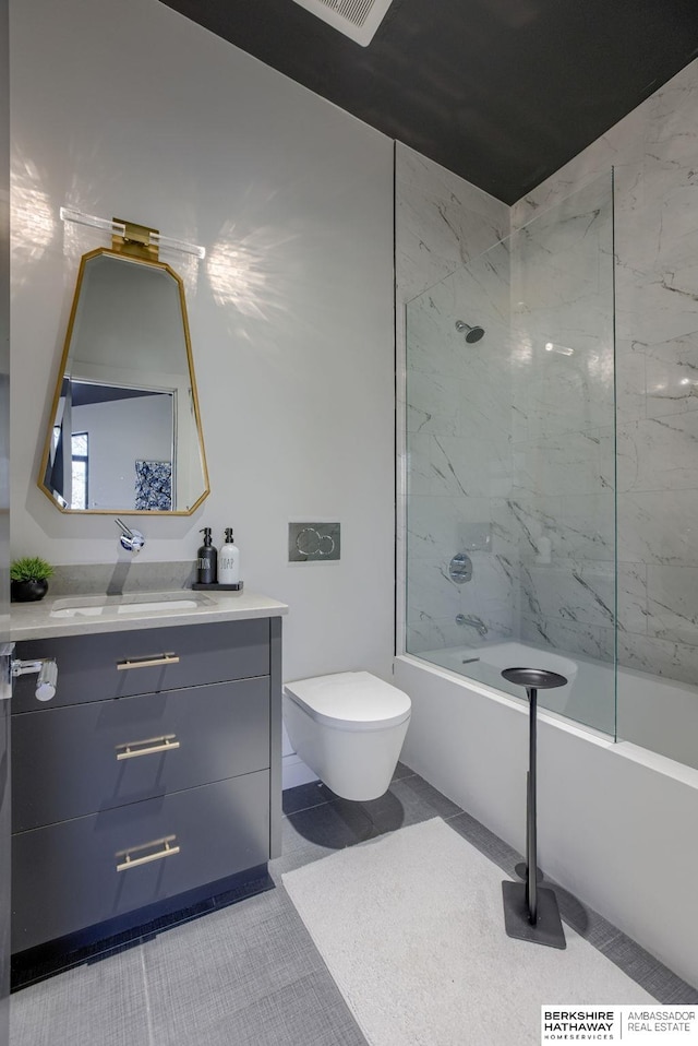 full bathroom with tile patterned floors, tiled shower / bath, vanity, and toilet