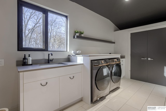 clothes washing area featuring cabinets, light tile patterned floors, sink, and washing machine and clothes dryer