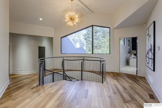 interior space with vaulted ceiling with beams, wood-type flooring, and an inviting chandelier