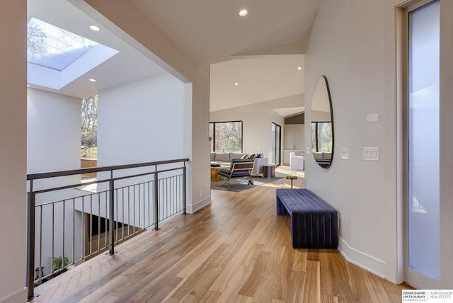 hall featuring light wood-type flooring and lofted ceiling with skylight