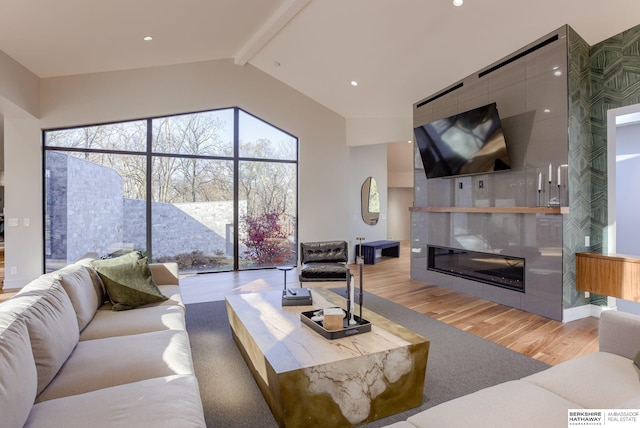 living room featuring a large fireplace, lofted ceiling with beams, and light hardwood / wood-style floors