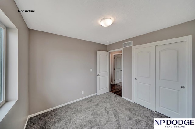 unfurnished bedroom with carpet floors, multiple windows, and a closet