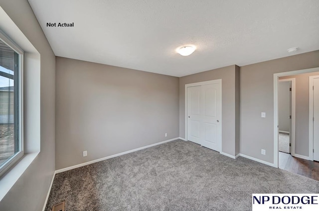 unfurnished bedroom featuring a textured ceiling, carpet floors, and a closet