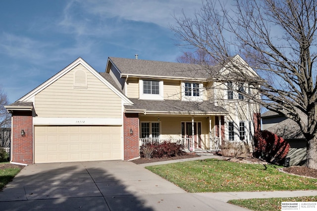 view of front of property with covered porch, a garage, and a front lawn