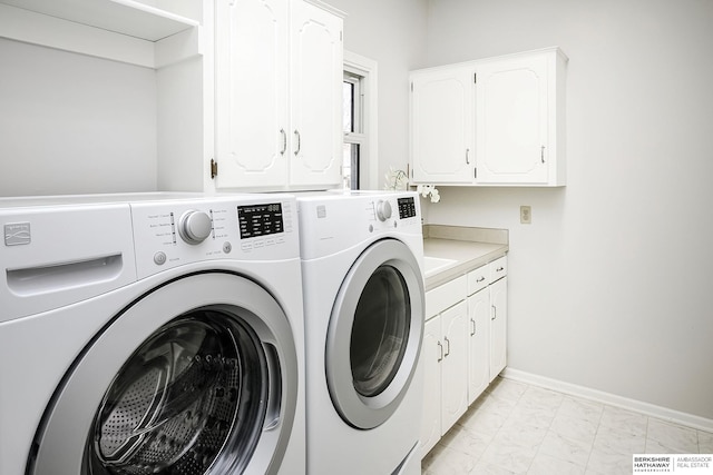 clothes washing area featuring separate washer and dryer and cabinets